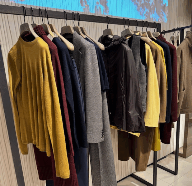 High-end clothing items hung on rack at boutique fashion store.