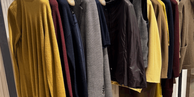 High-end clothing items hung on rack at boutique fashion store.