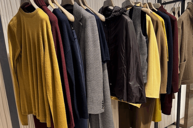 High-end clothing items hung on rack at boutique fashion store.